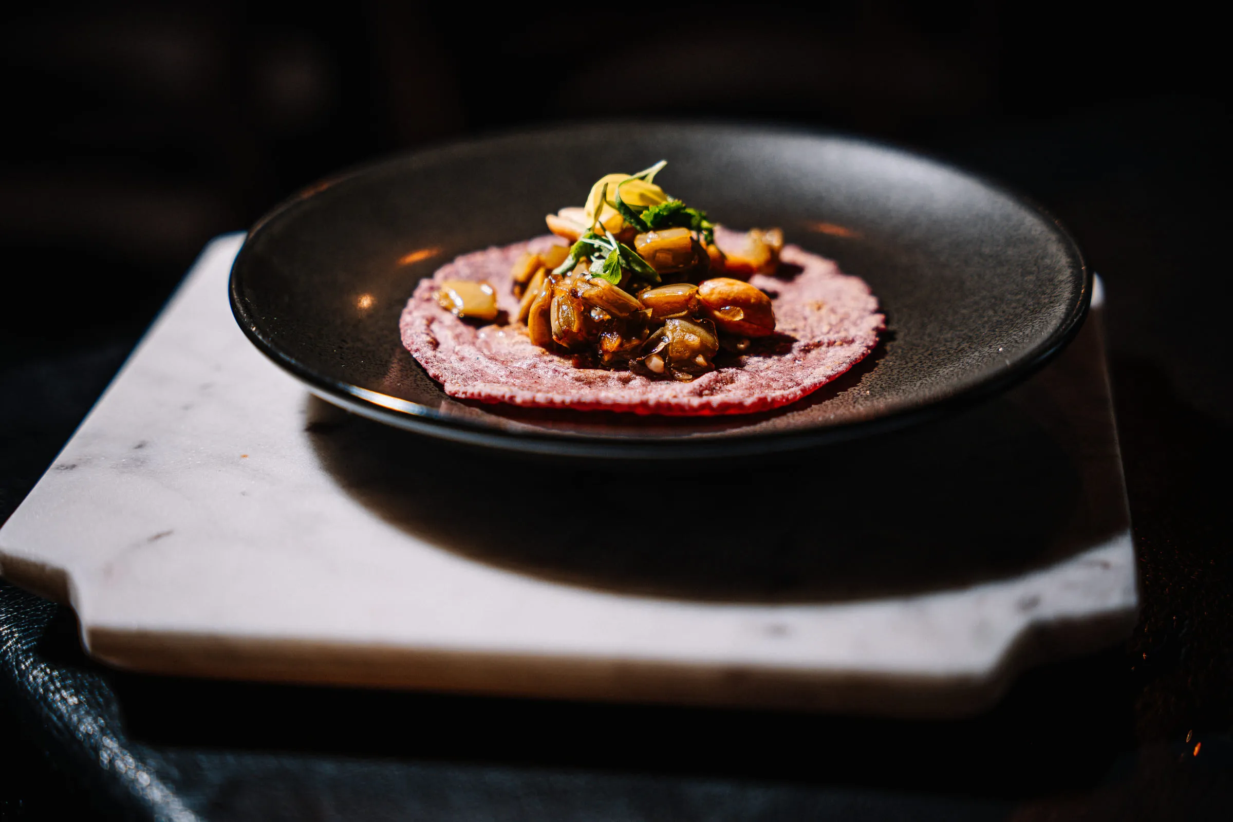 Mushroom tostada on black plate — Food photography by JP Media Groups